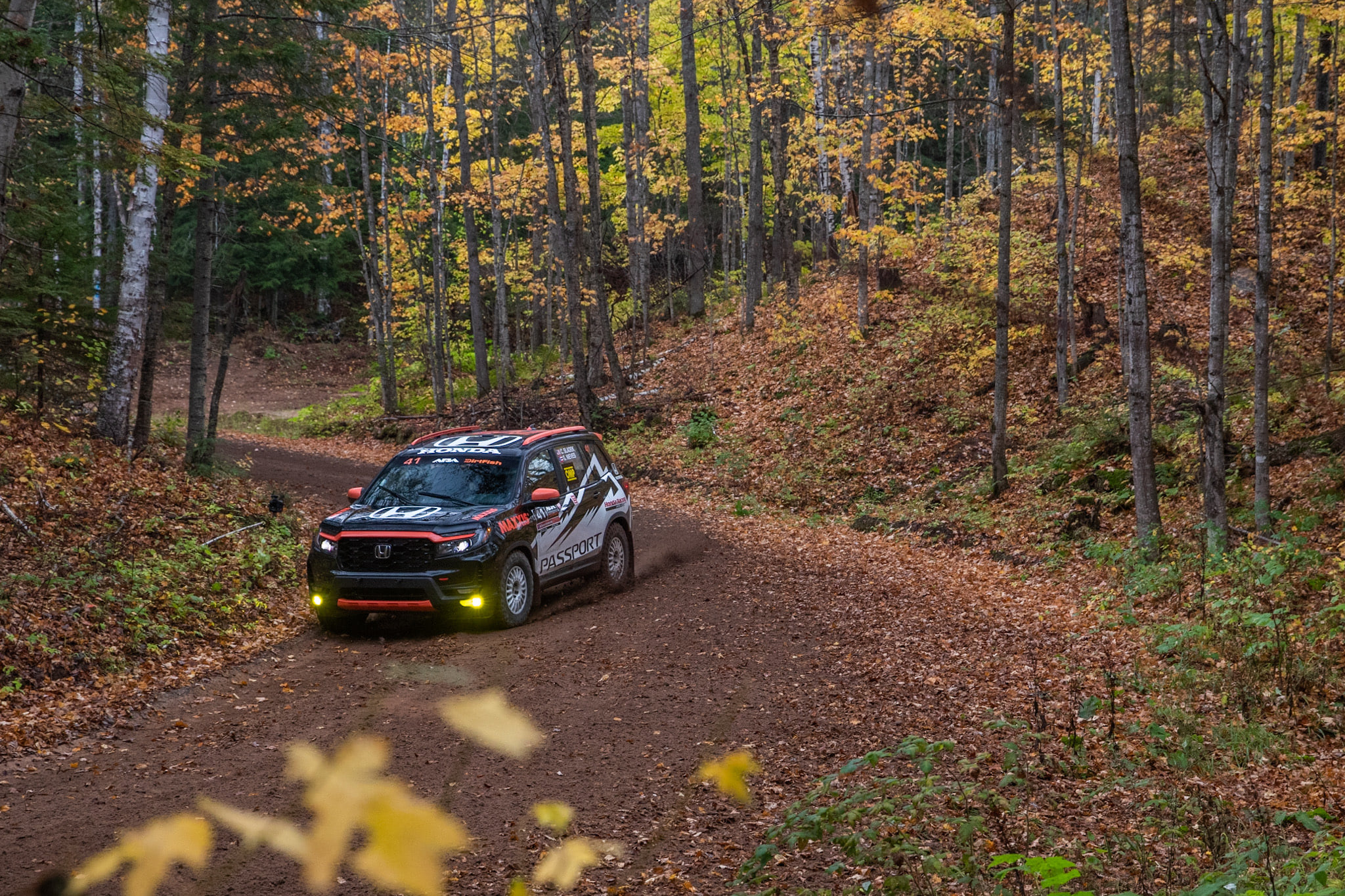 Honda Passport with rally-inspired Tridico vehicle wrap on a forest trail.